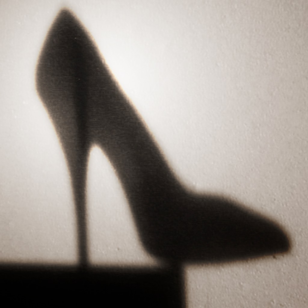 Shadow of a high-heeled shoe cast against a wall, the original photograph that inspired the ArtChangesLives(Dot)Com stiletto symbol.